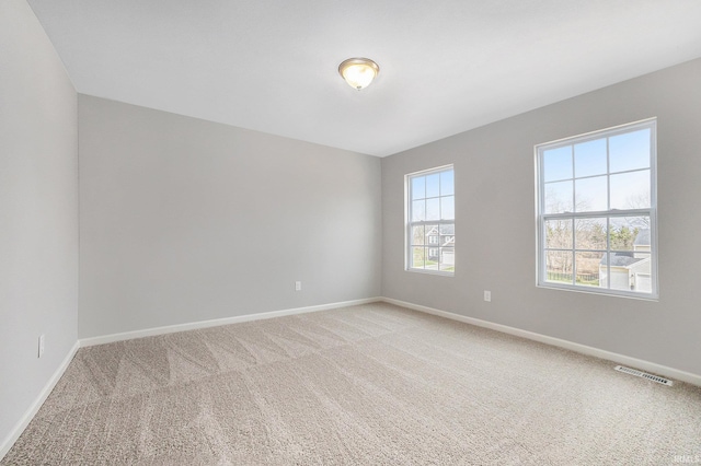 empty room with visible vents, baseboards, and light colored carpet