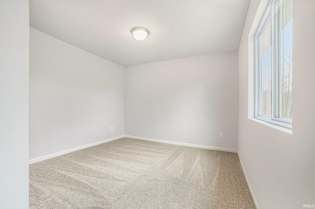 spare room featuring plenty of natural light, carpet flooring, and baseboards