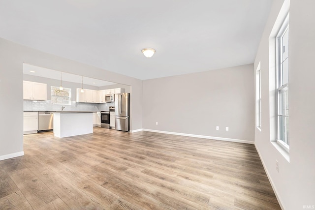 unfurnished living room featuring baseboards and light wood-type flooring