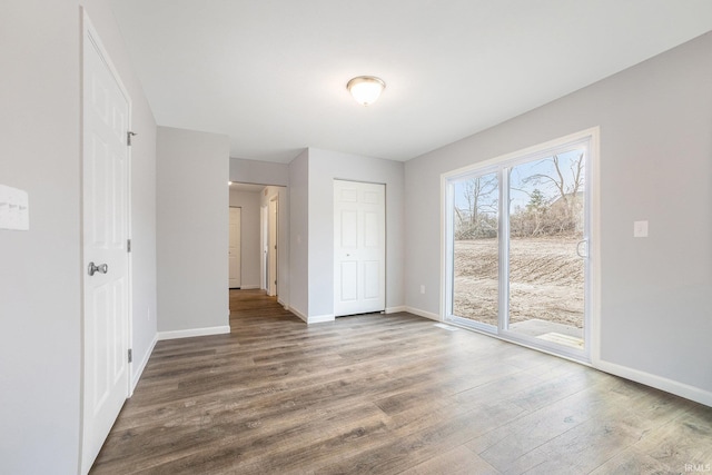 unfurnished bedroom with baseboards, access to outside, a closet, and wood finished floors