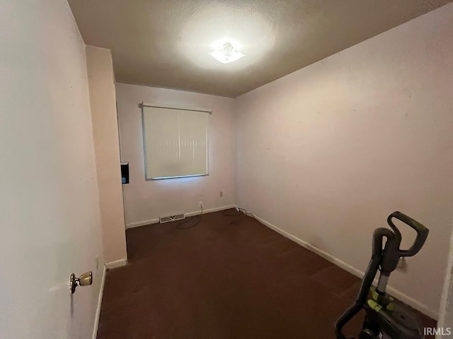 unfurnished room with visible vents, baseboards, and dark colored carpet