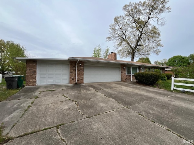 single story home with a garage, fence, a chimney, brick siding, and concrete driveway