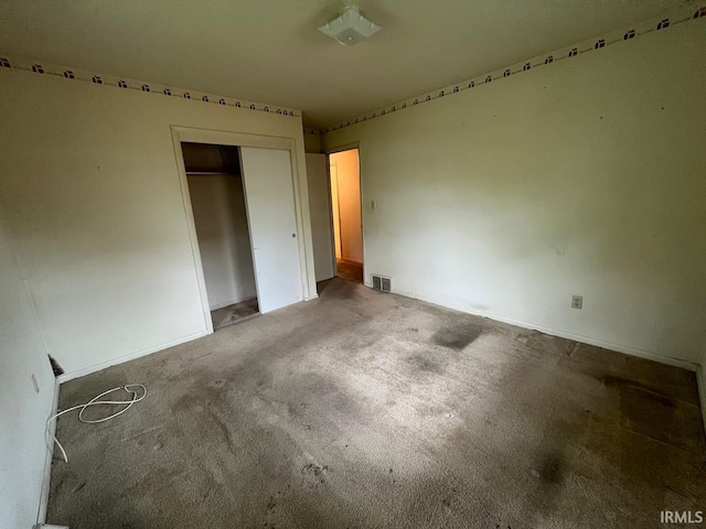 unfurnished bedroom with carpet flooring, baseboards, visible vents, and a closet