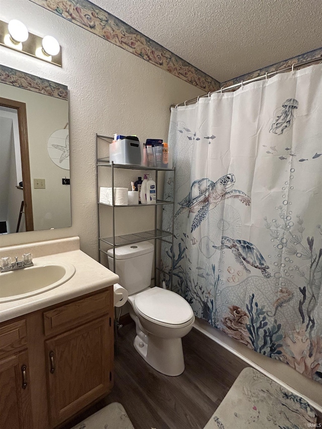 full bathroom with a textured ceiling, wood finished floors, vanity, toilet, and a textured wall