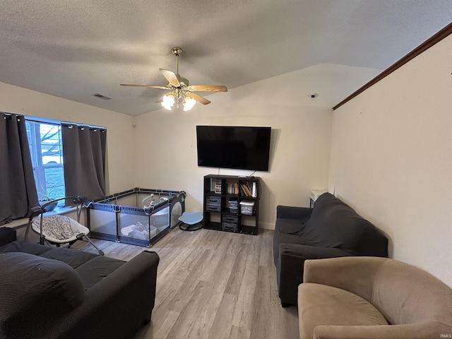 living area with a ceiling fan, baseboards, lofted ceiling, light wood-type flooring, and visible vents