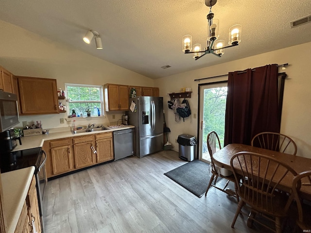 kitchen with visible vents, appliances with stainless steel finishes, light countertops, a sink, and a notable chandelier