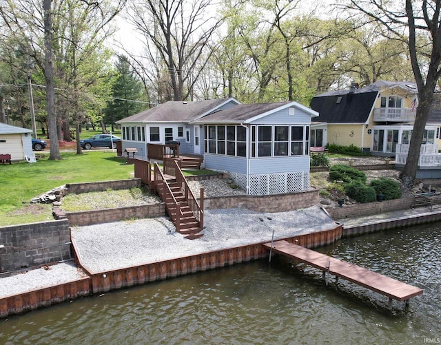 rear view of house featuring a yard, stairway, a sunroom, and a deck with water view