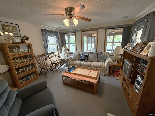 living room with a ceiling fan, carpet, visible vents, and a textured ceiling