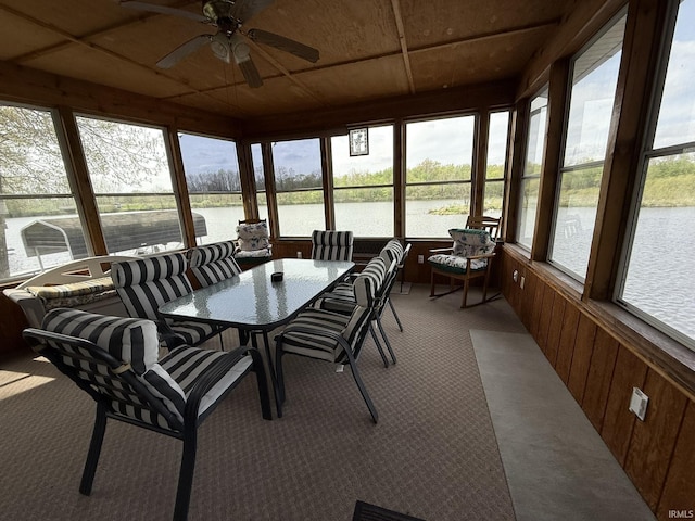 sunroom / solarium with wood walls, a water view, and carpet