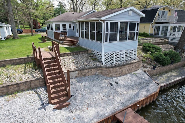 rear view of house with a lawn, a sunroom, and a deck with water view