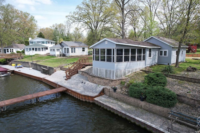 rear view of property featuring a water view, a yard, and a sunroom