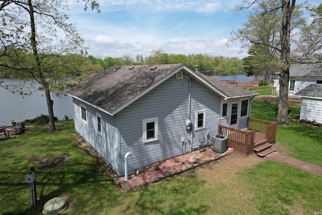 exterior space featuring a yard, a deck, cooling unit, and a shingled roof