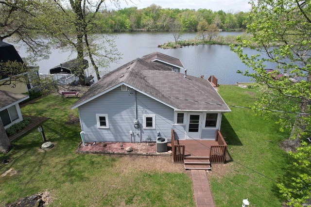 exterior space with a lawn, central air condition unit, a shingled roof, and a deck with water view