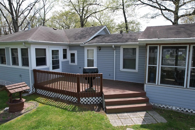 back of house featuring a lawn, a wooden deck, and a shingled roof
