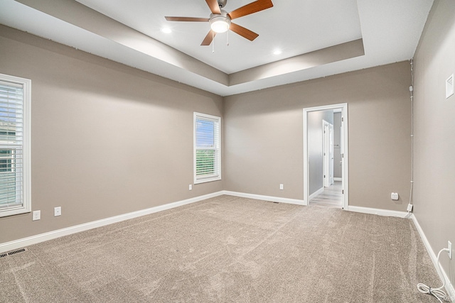 empty room with carpet floors, a ceiling fan, baseboards, and visible vents