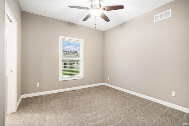 carpeted spare room featuring ceiling fan, visible vents, and baseboards