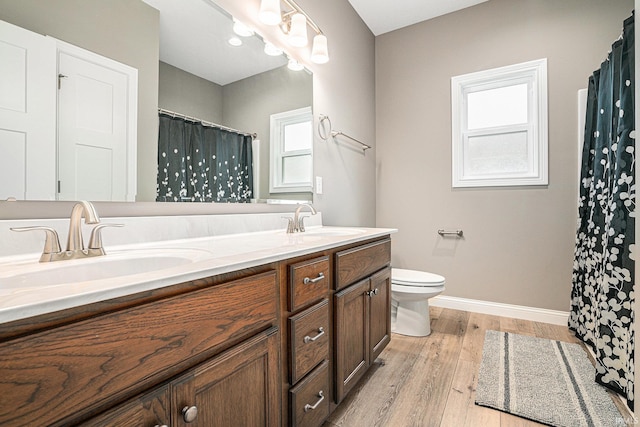 bathroom with a sink, baseboards, toilet, and wood finished floors
