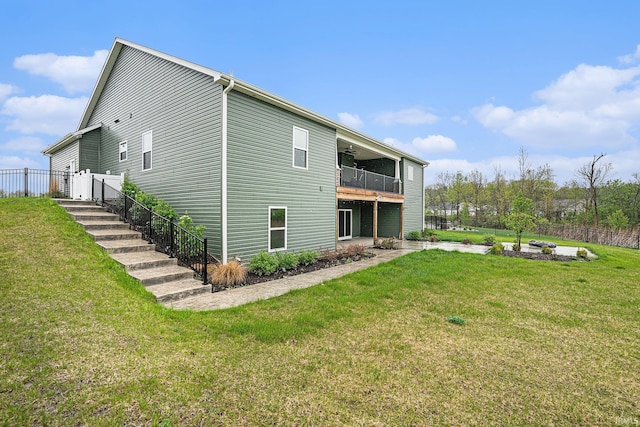 rear view of house featuring a yard, a balcony, and fence
