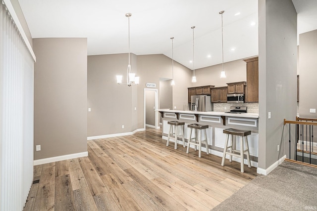 kitchen featuring light wood-style floors, a breakfast bar area, light countertops, stainless steel appliances, and pendant lighting