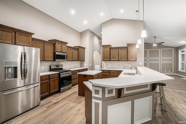kitchen with a sink, a breakfast bar area, high vaulted ceiling, stainless steel appliances, and light wood-type flooring