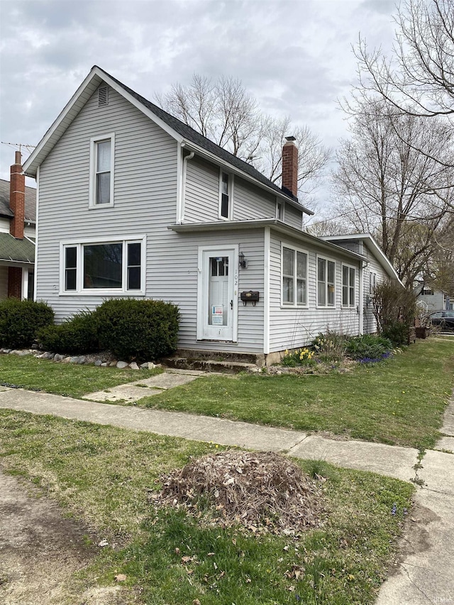 traditional-style home with a chimney and a front yard