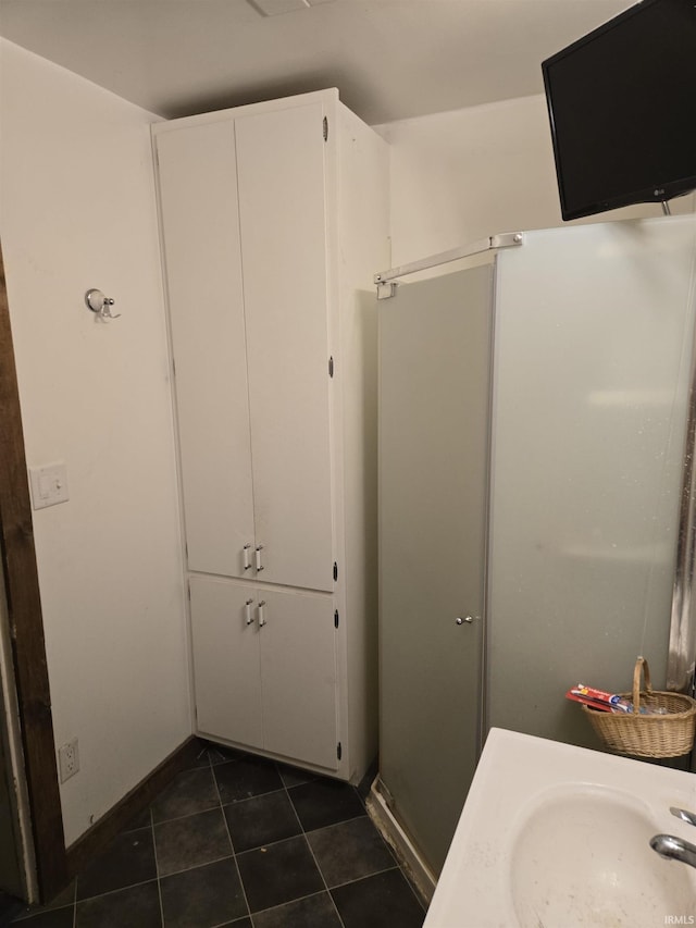 bathroom with a sink, tile patterned floors, and baseboards