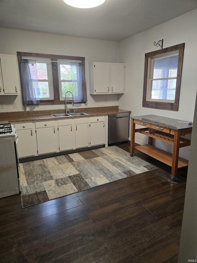 kitchen featuring stainless steel dishwasher, gas range gas stove, a sink, dark wood-style floors, and white cabinetry