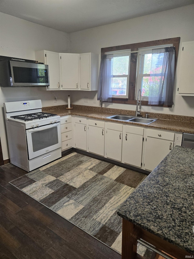 kitchen featuring dark wood-style floors, white range with gas cooktop, stainless steel microwave, white cabinetry, and a sink