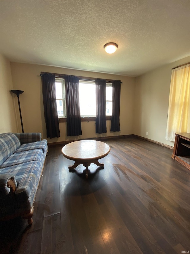 living room with baseboards, a textured ceiling, and wood finished floors