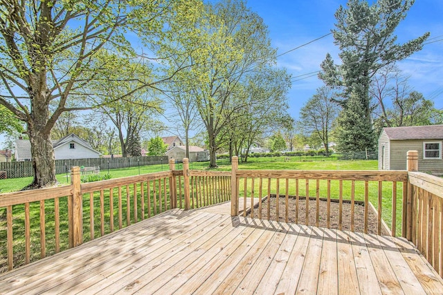wooden terrace featuring a storage unit, a fenced backyard, an outbuilding, and a yard