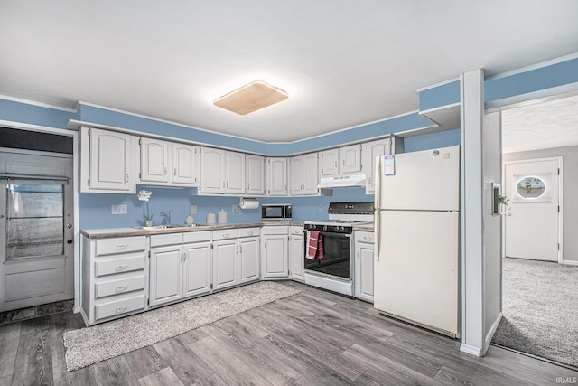 kitchen with a sink, range with gas stovetop, freestanding refrigerator, stainless steel microwave, and under cabinet range hood
