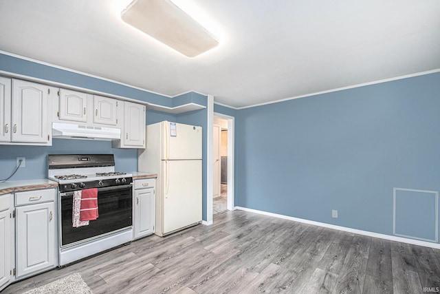 kitchen featuring light countertops, light wood-style flooring, freestanding refrigerator, under cabinet range hood, and gas range oven