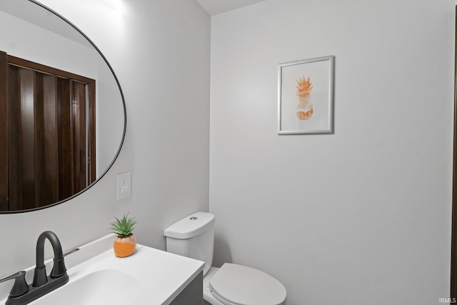 half bath featuring vanity and toilet