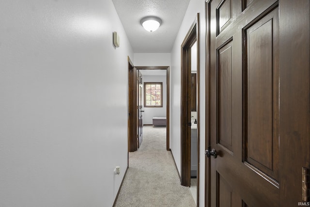 hallway featuring a textured ceiling and light carpet