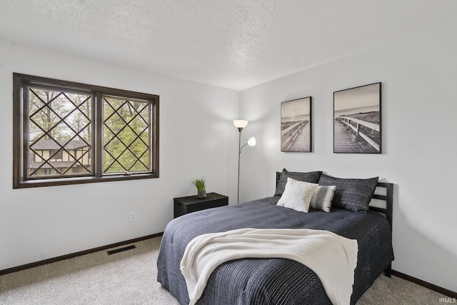 bedroom featuring baseboards, carpet flooring, a textured ceiling, and visible vents
