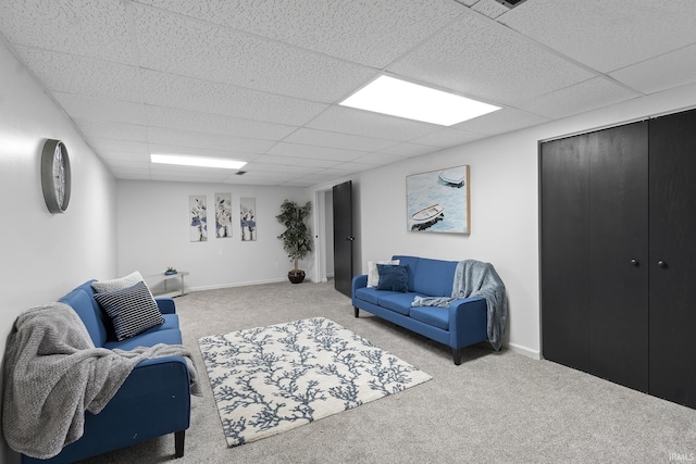 living room featuring baseboards, carpet, and a drop ceiling