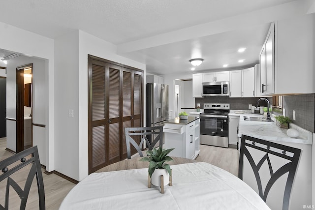 kitchen featuring a sink, light wood finished floors, white cabinetry, and stainless steel appliances