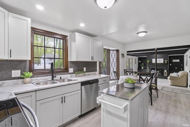 kitchen featuring stainless steel dishwasher, white cabinetry, plenty of natural light, and a sink