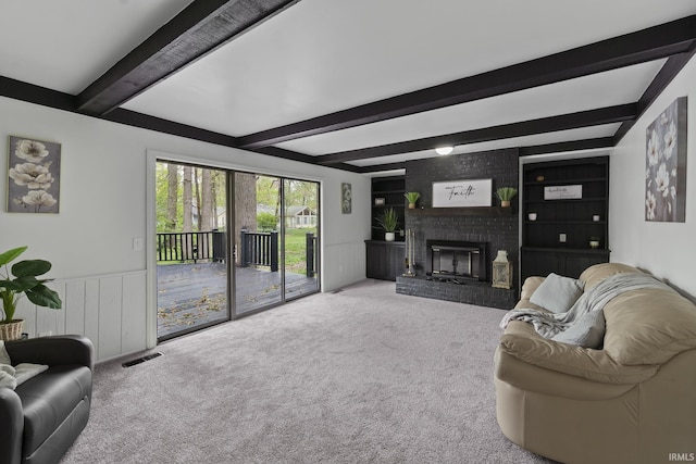 living area with carpet floors, beamed ceiling, visible vents, and a wainscoted wall