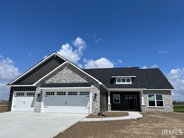 craftsman inspired home with stone siding, an attached garage, and driveway