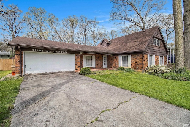 view of front of home with a shingled roof, a front lawn, aphalt driveway, a garage, and brick siding