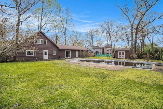 rear view of house featuring an outdoor structure, fence, a yard, and a storage unit