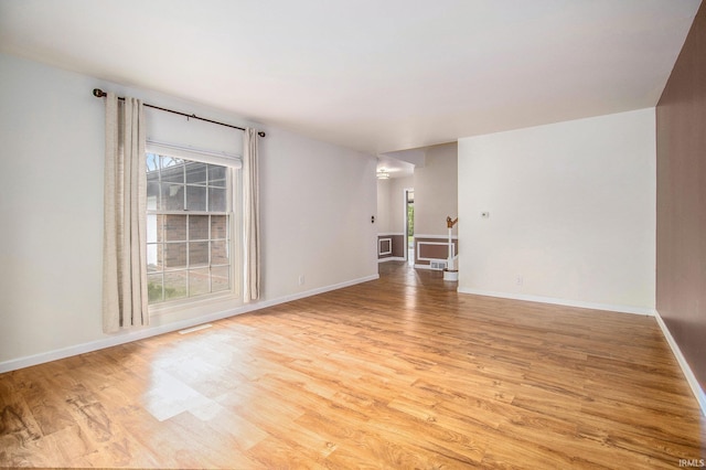 unfurnished room with light wood-style floors, plenty of natural light, and visible vents