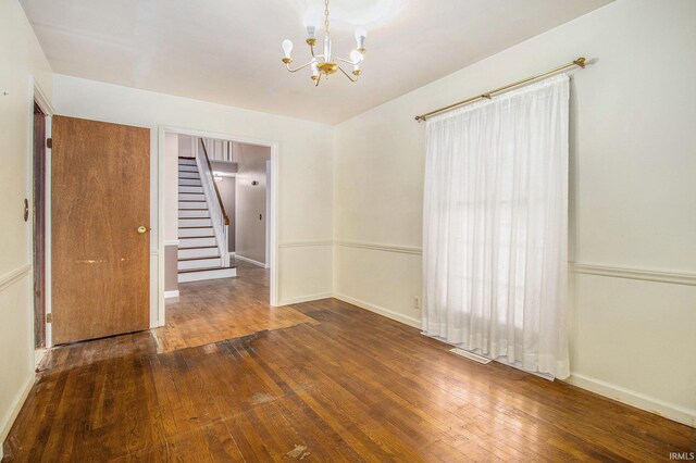 empty room featuring wood-type flooring, visible vents, stairs, baseboards, and a notable chandelier
