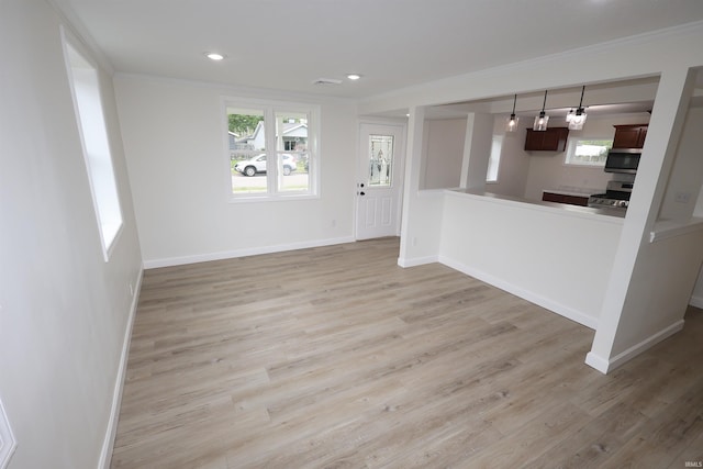 unfurnished living room featuring baseboards, ornamental molding, and light wood finished floors