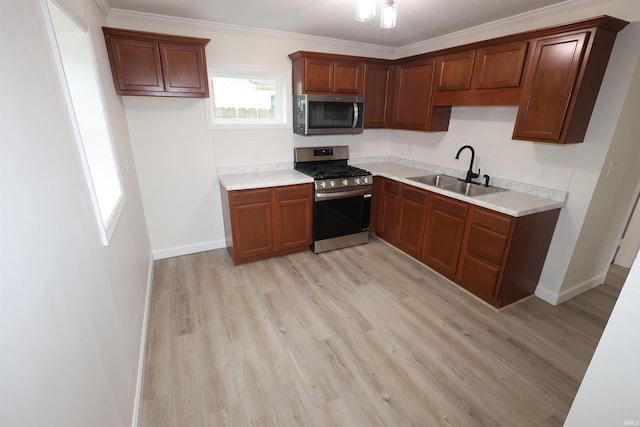 kitchen featuring baseboards, appliances with stainless steel finishes, a sink, and light wood-style floors