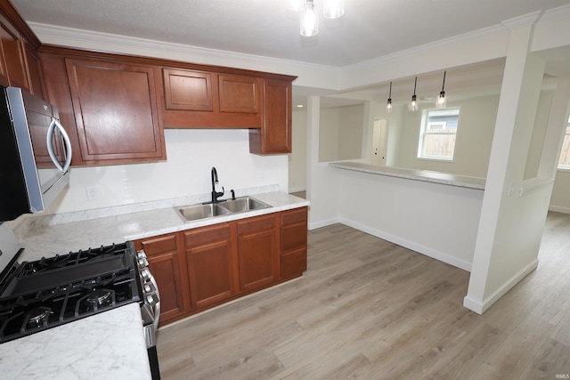 kitchen featuring ornamental molding, light countertops, a sink, light wood-style flooring, and appliances with stainless steel finishes