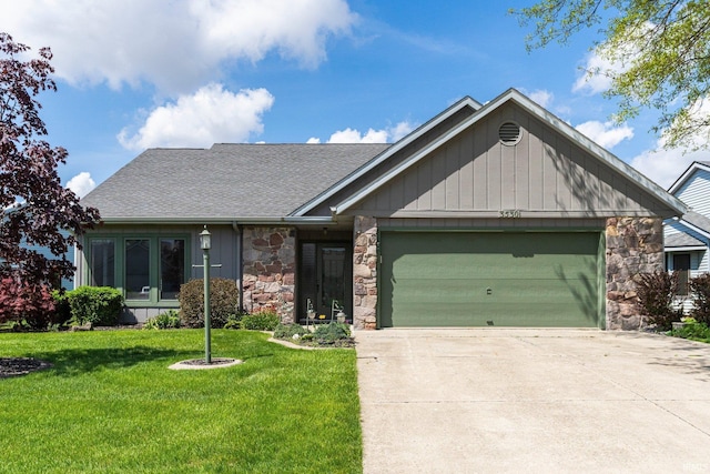view of front of house featuring driveway, roof with shingles, a garage, a front lawn, and stone siding