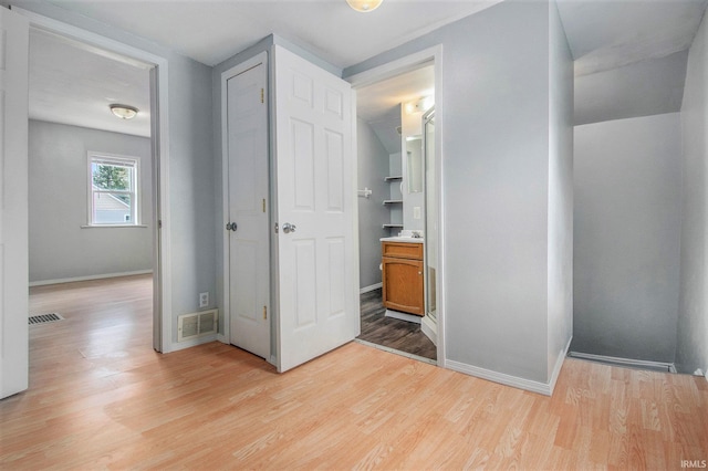 unfurnished bedroom featuring baseboards, connected bathroom, light wood-style flooring, and visible vents