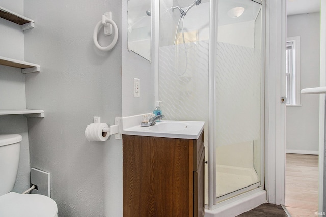 full bath featuring vanity, a stall shower, toilet, and wood finished floors